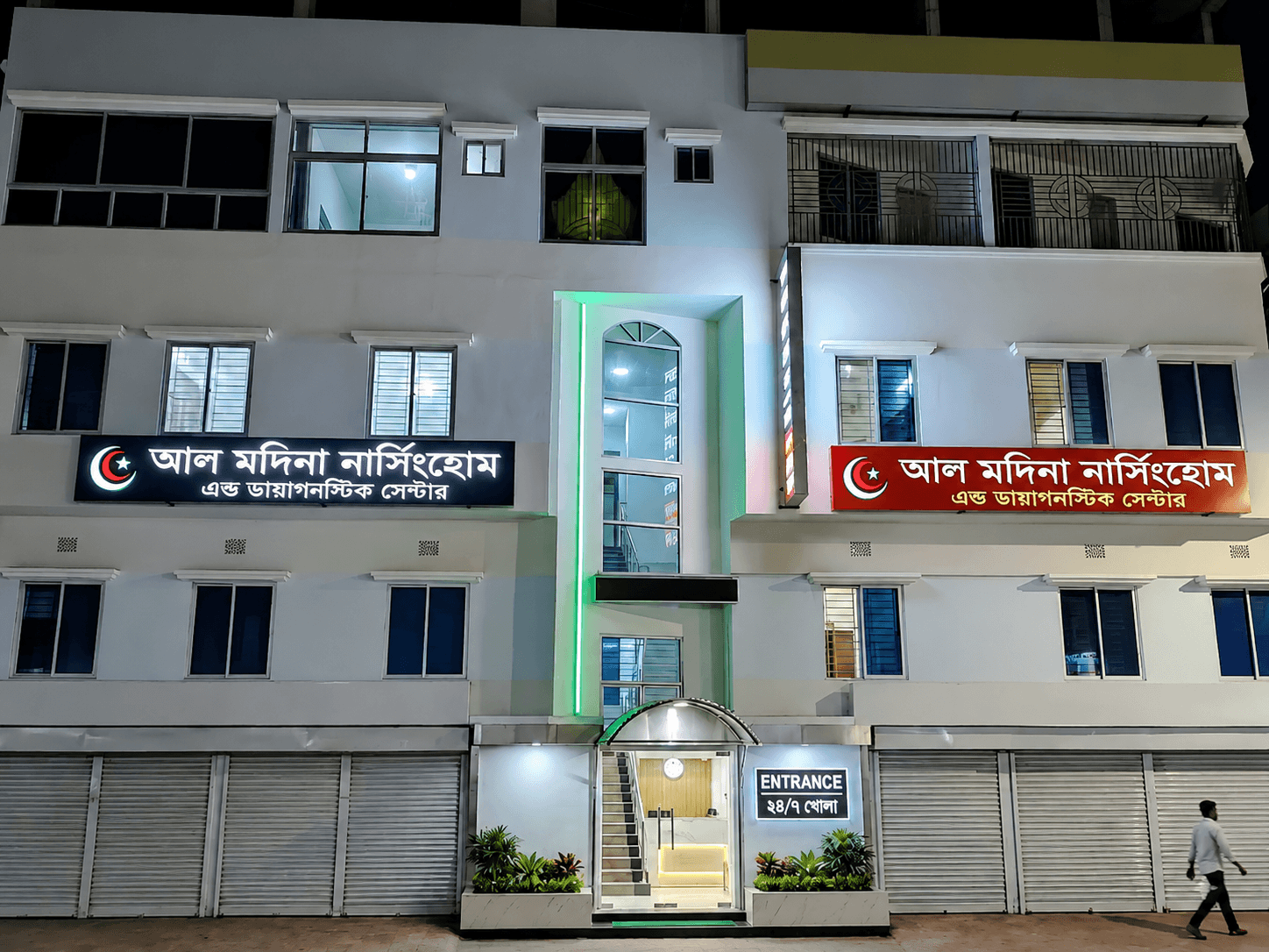 Illuminated exterior of the Al-Madina Nursing Home & Diagnostic Centre building at night with signage